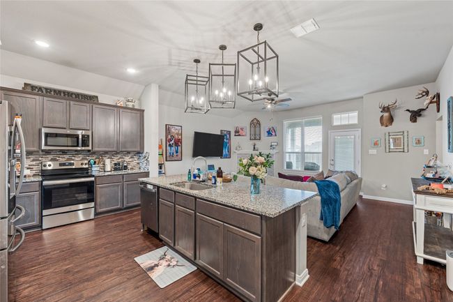 Kitchen with appliances with stainless steel finishes, a sink, dark wood-type flooring, dark brown cabinets, and recessed lighting | Image 12