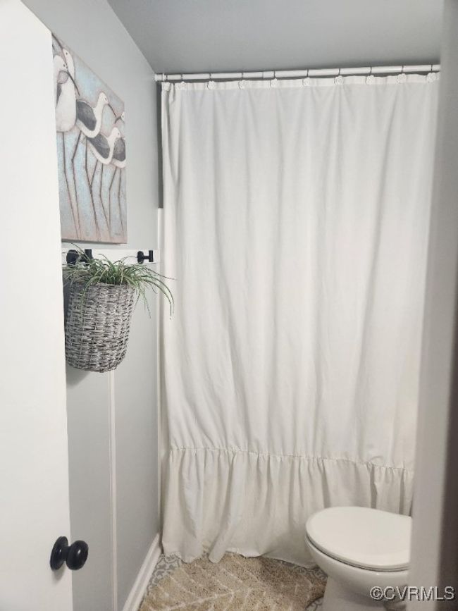 Bathroom featuring toilet and a shower with curtain | Image 13