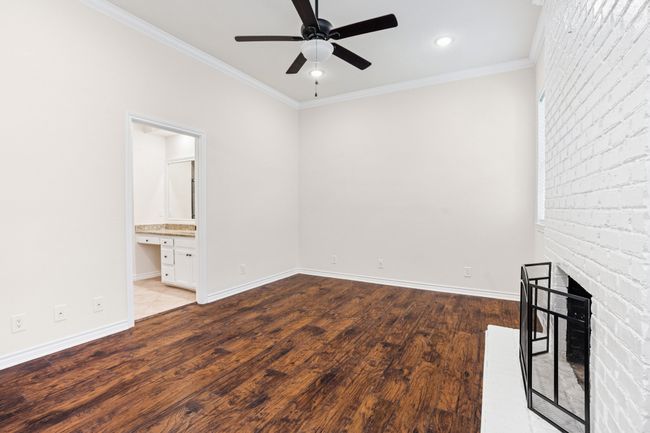 Unfurnished room with ceiling fan, wood finished floors, crown molding, a brick fireplace, and recessed lighting | Image 14