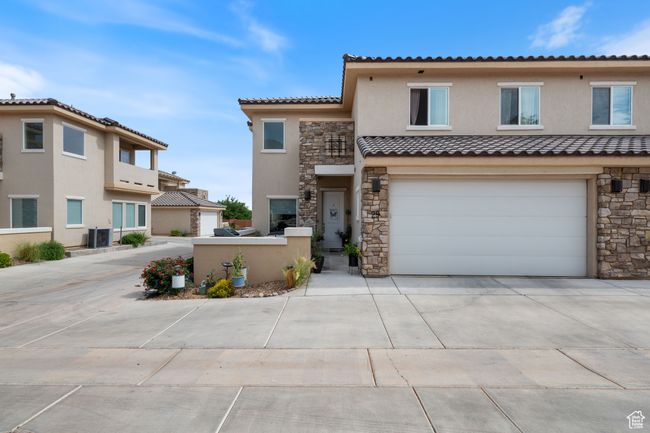 Multi unit property with stone siding, driveway, stucco siding, a tiled roof, and an attached garage | Image 4