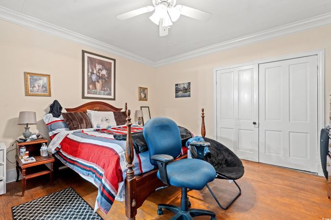 Bedroom featuring crown molding, wood finished floors, a closet, ceiling fan, and a desk | Image 37