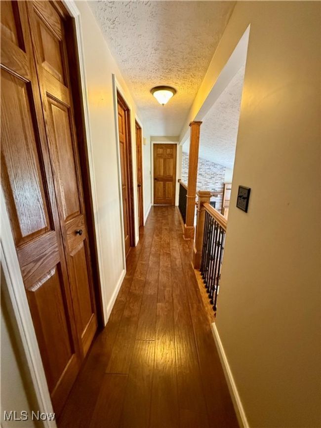 Hall featuring an upstairs landing, a textured ceiling, dark wood-style flooring, and baseboards | Image 27