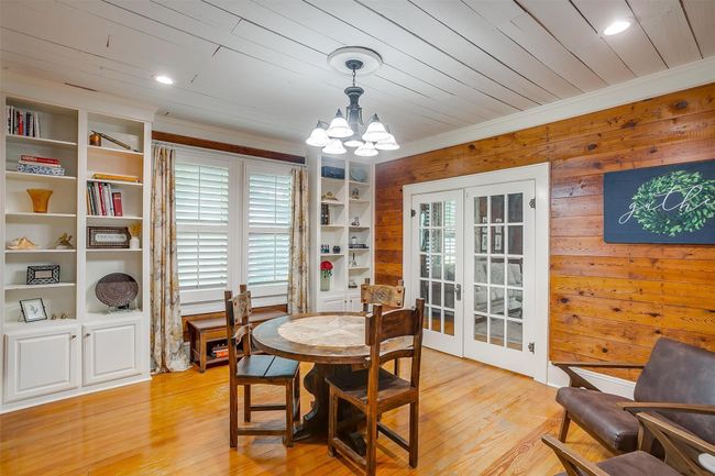 Dining area with french doors, healthy amount of natural light, a chandelier, light wood-type flooring, and wooden walls | Image 16