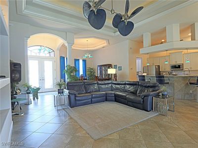 Living room featuring a towering ceiling, french doors, ceiling fan, crown molding, and light tile patterned floors | Image 2