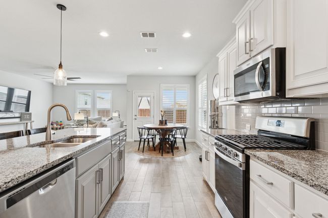 Kitchen featuring appliances with stainless steel finishes, backsplash, light wood-style floors, recessed lighting, and light stone countertops | Image 8