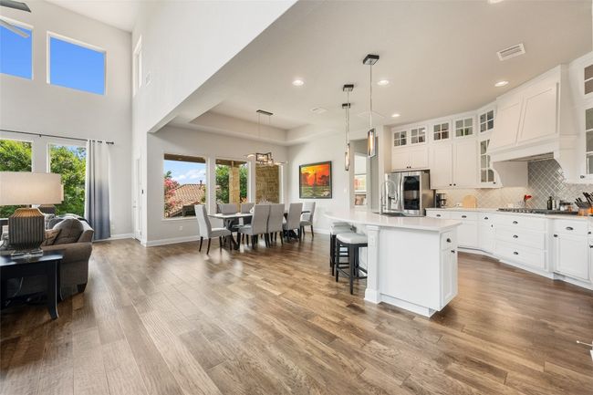 Kitchen with stainless steel fridge with ice dispenser, open floor plan, wood finished floors, light countertops, and a kitchen island with sink | Image 8