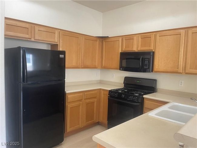 Kitchen with black appliances, light countertops, and light wood-style floors | Image 11