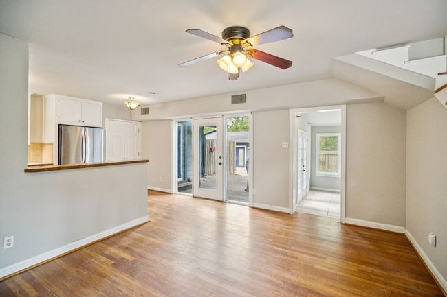 Unfurnished living room featuring light wood finished floors, a ceiling fan, and stairs | Image 10