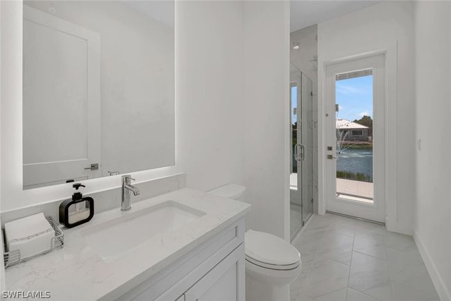Pool Bath featuring walk in frameless glass shower, Quartz vanity top with a frameless, backlit, anti-fog mirror and tile patterned floor. | Image 15