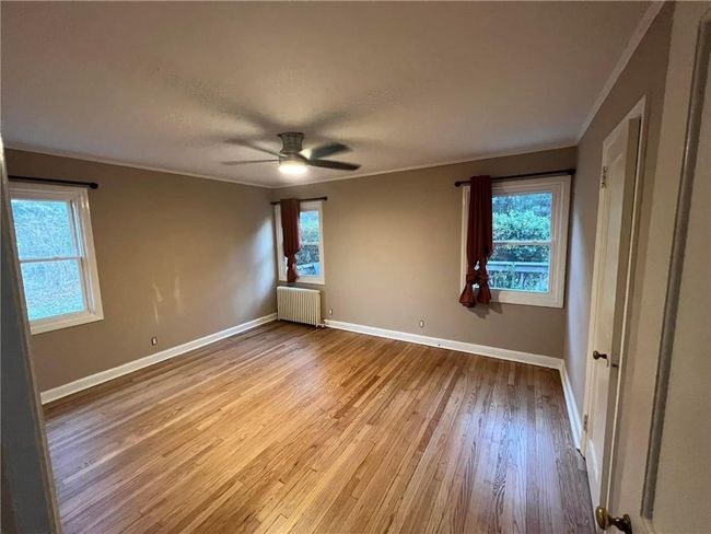 Empty room with ornamental molding, ceiling fan, radiator, and hardwood / wood-style flooring | Image 5