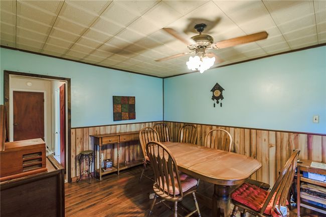 Dining area with a ceiling fan, wainscoting, wood finished floors, and wooden walls | Image 16
