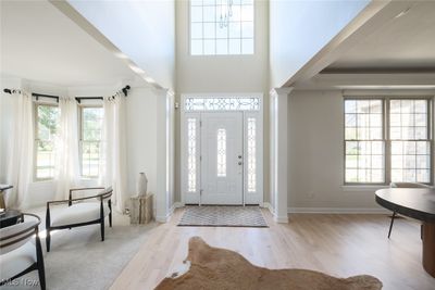 Entrance foyer with ornate columns, crown molding, a high ceiling, and light wood-type flooring | Image 2