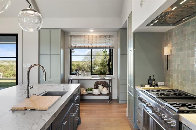 This is the kitchen layout of a chef's dream. With views of the front and rear yard through two large windows, as well as being fully open to the dining and living rooms, this kitchen is the heart of the home. Storage space is seemingly unlimited and neatly tucks away all serving pieces and appliances discreetly. | Image 10