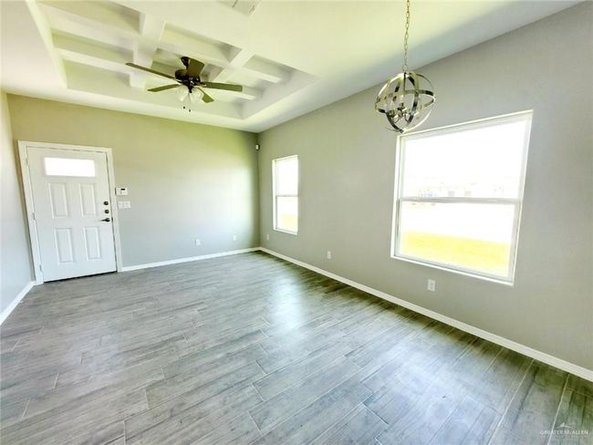 Spare room featuring coffered ceiling, a chandelier, ceiling fan, wood finished floors, and beam ceiling | Image 10