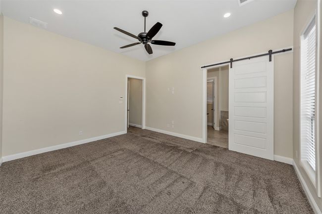 Unfurnished bedroom with a barn door, baseboards, visible vents, and carpet floors | Image 21
