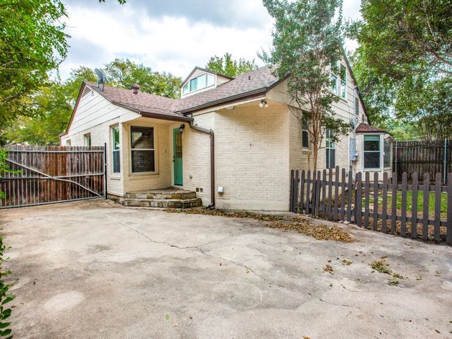 View of property exterior with a gate, brick siding, a fenced front yard, and roof with shingles | Image 24