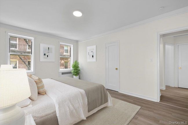 Bedroom featuring wood finished floors, crown molding, and radiator | Image 12
