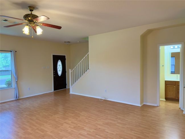 Unfurnished living room featuring light wood-style flooring, ceiling fan, and stairs | Image 13