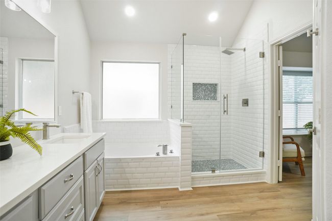 Full bath featuring vanity, vaulted ceiling, a garden tub, a shower stall, and wood finished floors | Image 17