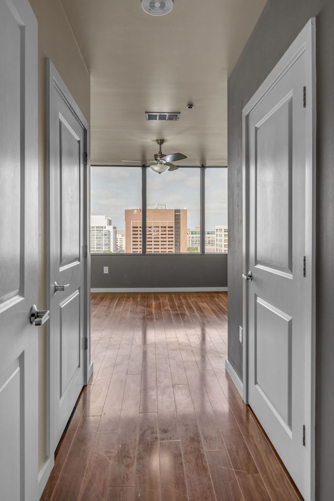Hall with baseboards, dark wood-type flooring, and visible vents | Image 11