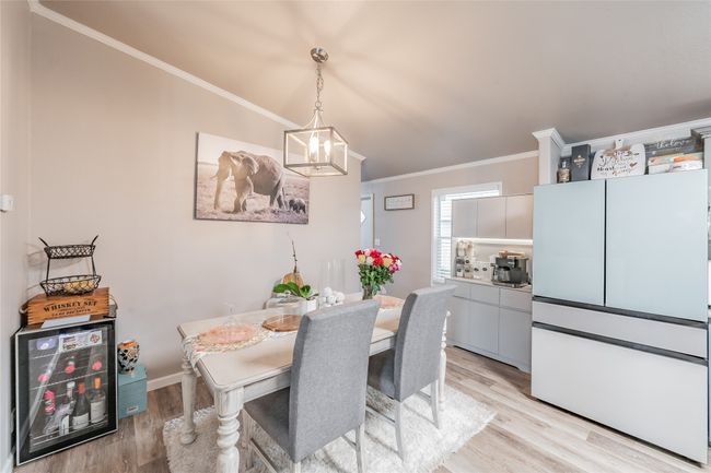 Dining space featuring light wood-style floors, ornamental molding, and a chandelier | Image 14