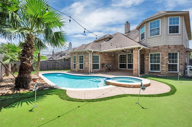 Luxurious pool and spa with surrounding artificial turf and a putting green. Perfect for relaxation and recreation. | Image 38
