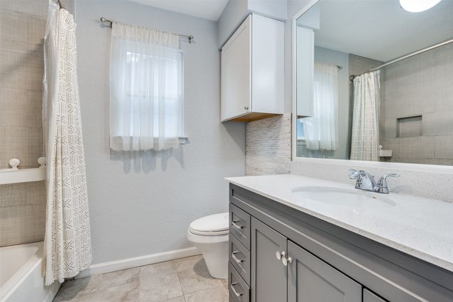 Full bathroom featuring tile patterned flooring, toilet, vanity, and shower / tub combo with curtain | Image 21