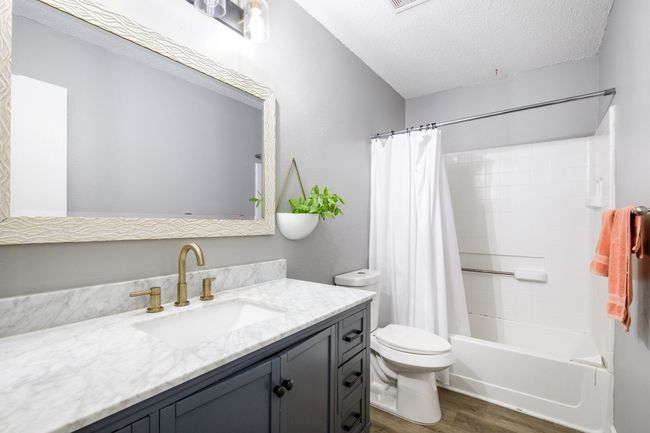 Full bathroom with wood finished floors, vanity, shower / bath combo with shower curtain, and a textured ceiling | Image 17
