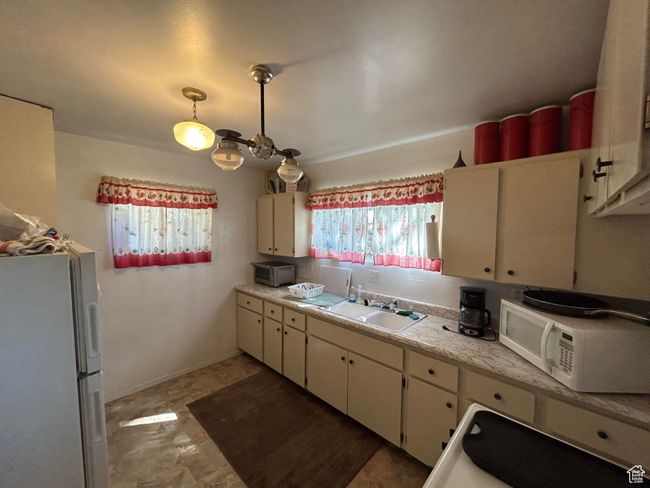 Kitchen featuring white appliances, light countertops, and white cabinetry | Image 12