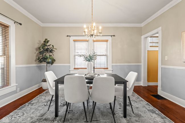 dining room with crown molding, dark wood-type flooring, and a chandelier | Image 12