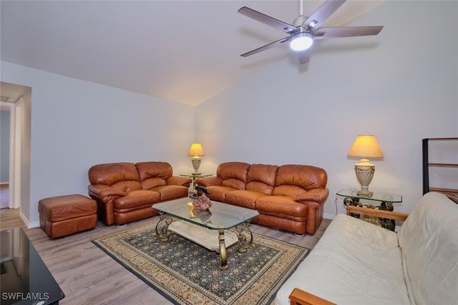 Living area featuring a ceiling fan, wood finished floors, and lofted ceiling | Image 6