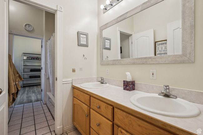 Bathroom featuring tile patterned floors, a shower with curtain, a sink, and double vanity | Image 33
