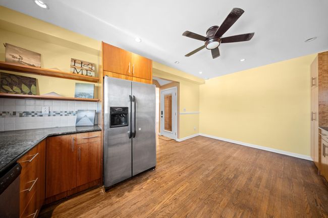 Kitchen featuring appliances with stainless steel finishes, open shelves, wood finished floors, a ceiling fan, and tasteful backsplash | Image 13