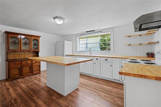 Kitchen featuring butcher block countertops, white appliances, wood finished floors, and open shelves | Image 8