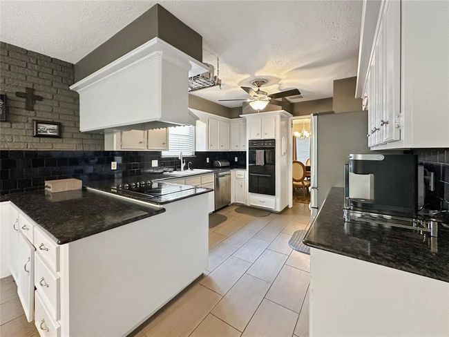 This kitchen boasts ample counter space and cabinetry, offering the perfect setup for meal prep, hosting, or casual family dining. | Image 15