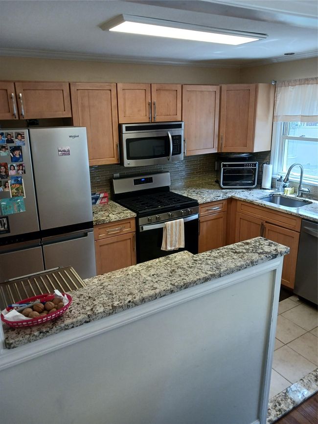 Kitchen featuring fridge, a sink, dishwashing machine, a toaster, and gas range | Image 12