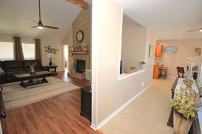 Living room with baseboards, high vaulted ceiling, a fireplace, & ceiling fan. | Image 14