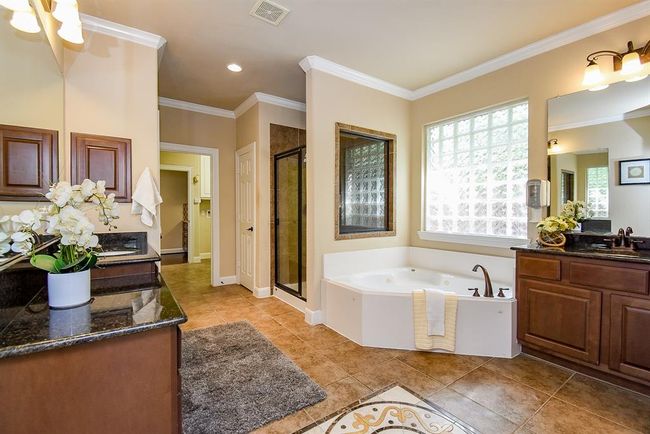 Finished with elegant tiling, the primary bathroom features dual vanities, a soaking tub, and a separate glass-enclosed shower. The thoughtful layout and details offer everyday luxury. | Image 24