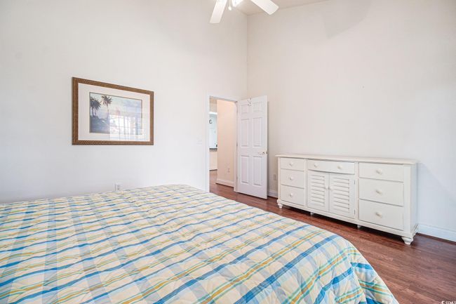 Bedroom with dark wood-style floors, a towering ceiling, a ceiling fan, and baseboards | Image 16
