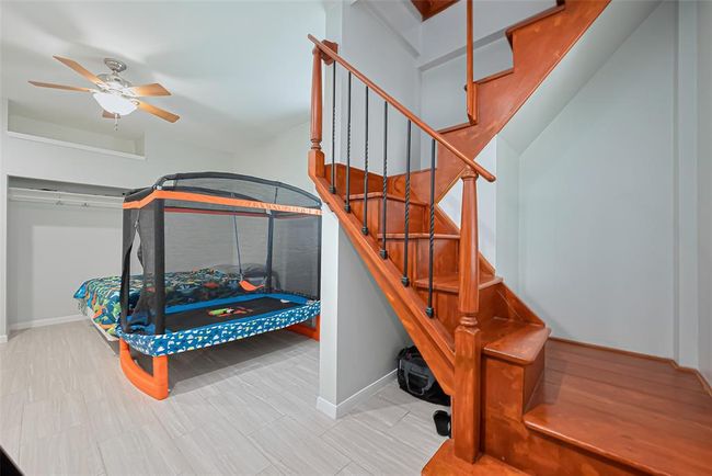 A wooden staircase with iron balusters, leading to a lower level where you will find a bonus room, perfect for a child's room or guest space. | Image 24