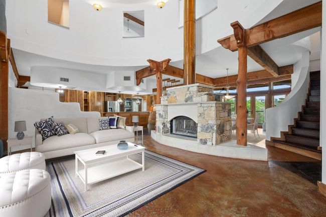 Living room featuring finished concrete floors, stairway, and a stone fireplace | Image 4