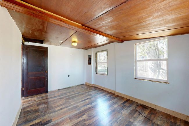 Spare room featuring vaulted ceiling with beams, wooden ceiling, wood finished floors, and baseboards | Image 12