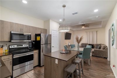 Kitchen featuring ceiling fan, decorative light fixtures, stainless steel appliances, and dark hardwood / wood-style flooring | Image 3