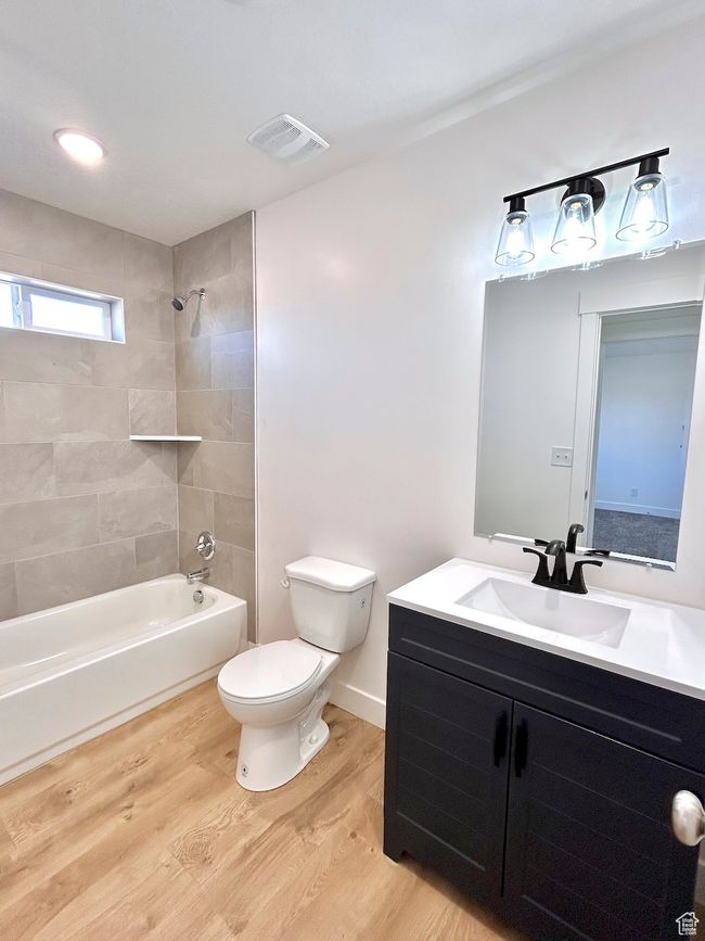 Full bath featuring wood finished floors, bathtub / shower combination, toilet, vanity, and visible vents | Image 14