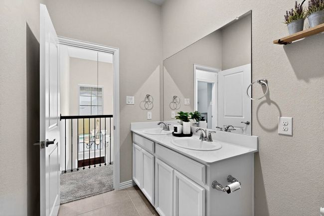 Bathroom featuring a textured wall, double vanity, and light tile patterned floors | Image 29