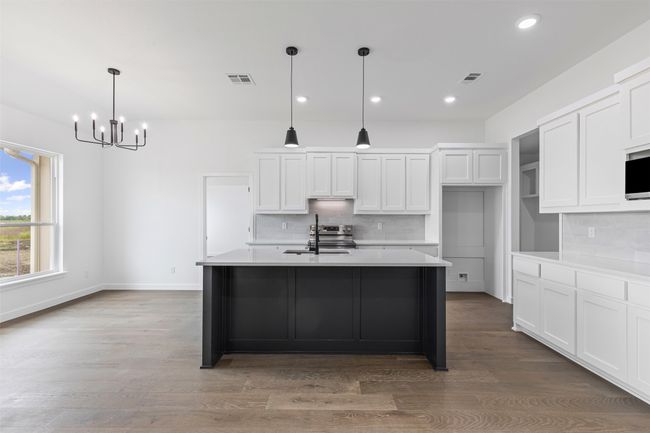 Kitchen with visible vents, decorative backsplash, white cabinets, a sink, and a notable chandelier | Image 14