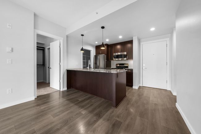 Kitchen with stainless steel appliances, a peninsula, dark wood-type flooring, dark brown cabinetry, and recessed lighting | Image 26