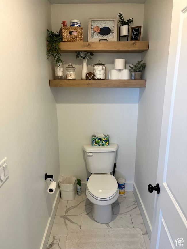 Bathroom with marble look tile flooring, toilet, and baseboards | Image 17
