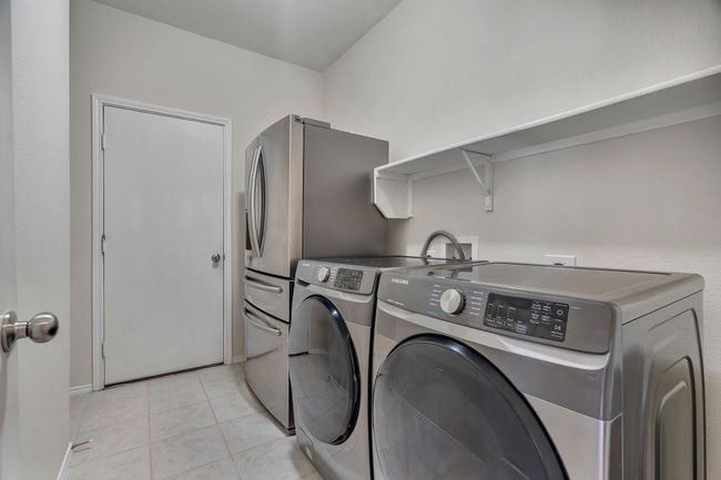 Laundry room featuring washing machine and clothes dryer and light tile patterned floors | Image 25