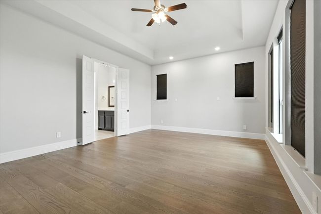 Unfurnished room featuring a ceiling fan, recessed lighting, wood finished floors, and a raised ceiling | Image 21